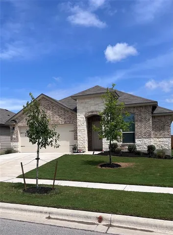 a view of a white house with a big yard and potted plants