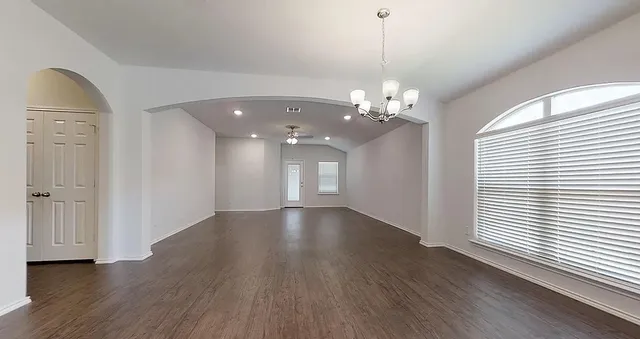 a view of a livingroom with a chandelier wooden floor and windows