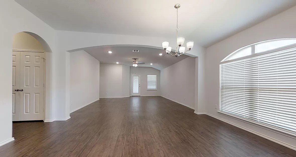 1828 T H Johnson Drive Taylor, TX 76574 - Photo 2 of 11 a view of a livingroom with a chandelier wooden floor and windows