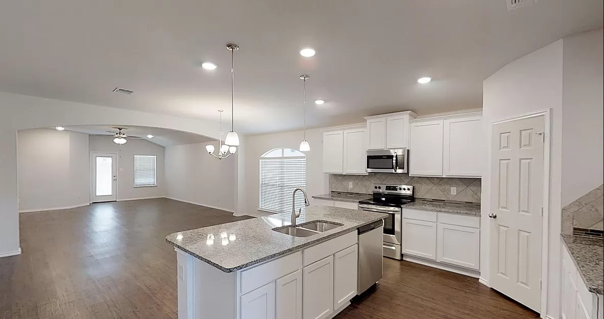 1828 T H Johnson Drive Taylor, TX 76574 - Photo 4 of 11 a kitchen with stainless steel appliances granite countertop a sink stove cabinets and wooden floor
