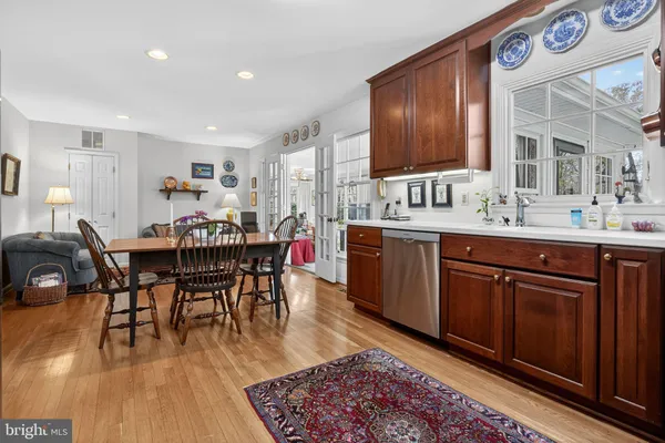 a dining hall with granite countertop a sink dishwasher a dining table and chairs with wooden floor