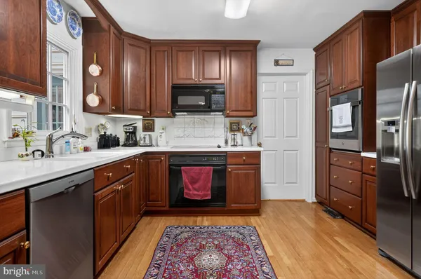 a kitchen with stainless steel appliances granite countertop a refrigerator a stove top oven and sink with wooden floor