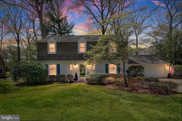 a front view of a house with a yard and a tree