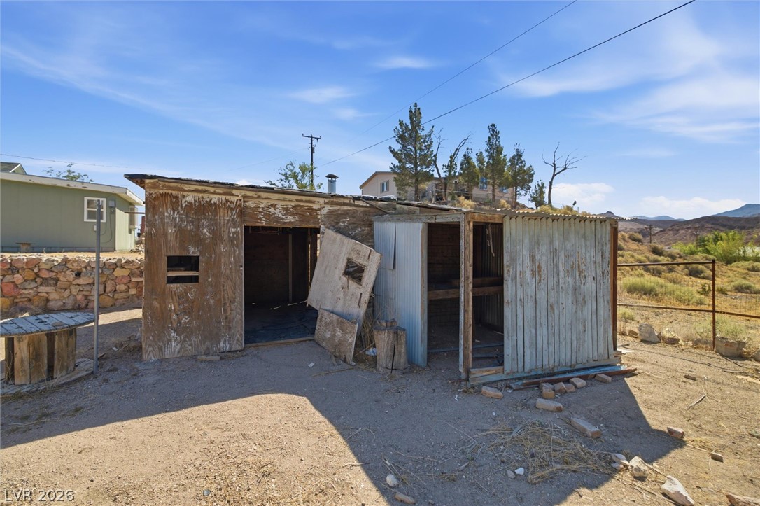 405 Main Street Beatty, NV 89003 - Photo 24 of 28 A rustic outbuilding sits against a backdrop of distant hills and a clear desert sky.