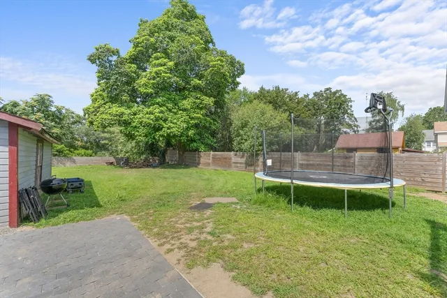 a view of a house with a yard and a large tree
