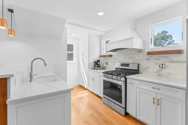 a kitchen with white cabinets stainless steel appliances and wooden floor