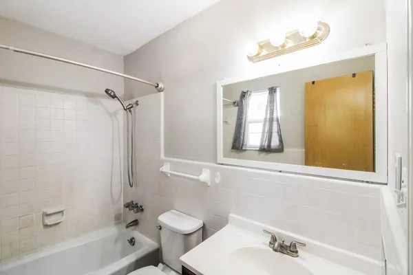 a bathroom with a bathtub shower sink vanity and a toilet