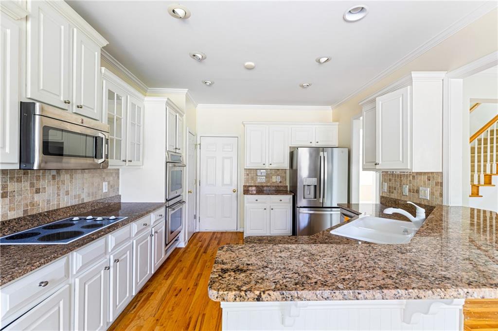 1355 Chattahoochee Run Drive Suwanee, GA 30024 - Photo 11 of 57 a large kitchen with kitchen island granite countertop a large counter top appliances a sink a window and cabinets