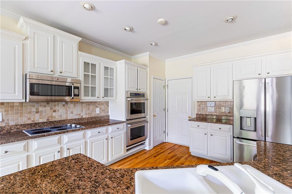 1355 Chattahoochee Run Drive Suwanee, GA 30024 - Photo 12 of 57 a kitchen with stainless steel appliances kitchen island granite countertop a refrigerator sink and cabinets