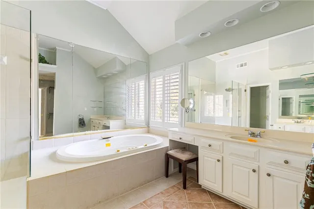 a bathroom with a tub a sink and a large mirror