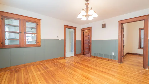 a view of an empty room with wooden floor and a ceiling fan