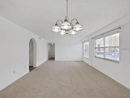 a view of a livingroom with a chandelier fan and windows