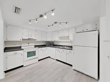 a kitchen with granite countertop white cabinets and white appliances