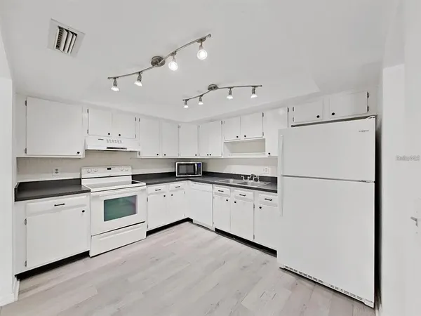 a kitchen with granite countertop white cabinets and white appliances
