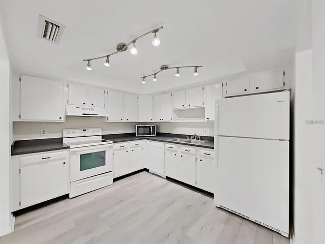 a kitchen with granite countertop white cabinets and white appliances