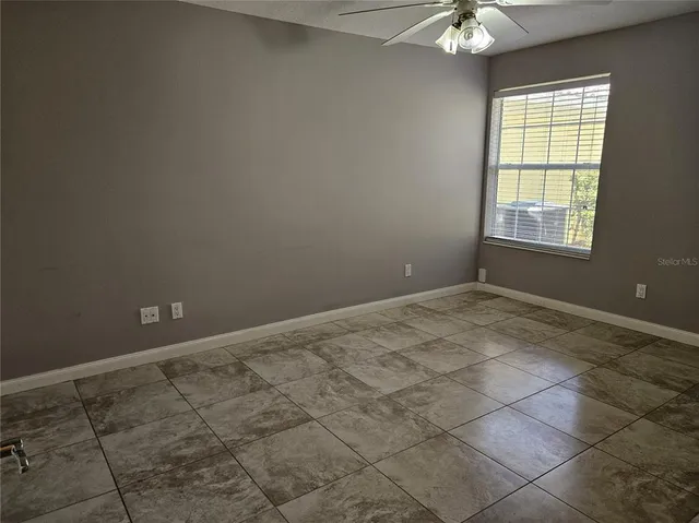 an empty room with a chandelier fan and windows