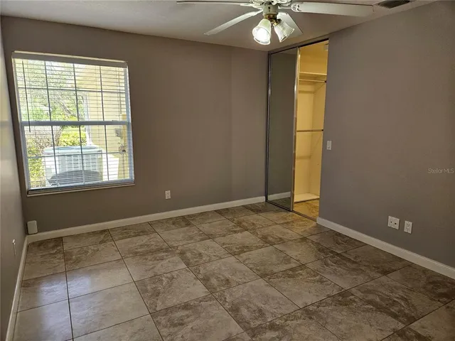 an empty room with closet and a chandelier fan