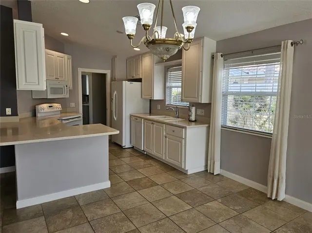 a kitchen with stainless steel appliances granite countertop a sink a stove a refrigerator a washer dryer and a dining table