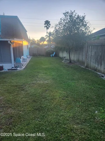 a view of a house with a small yard plants and large tree