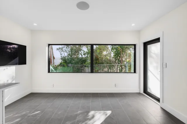 a view of an empty room with a window and a flat screen tv
