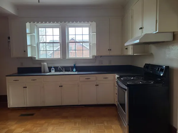a kitchen with granite countertop white cabinets and a stove