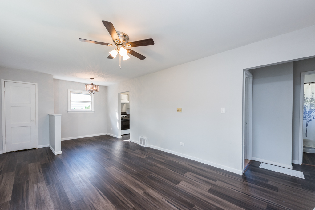 1636 Rice Street Waukegan, IL 60087 - Photo 5 of 26 an empty room with wooden floor a ceiling fan and windows