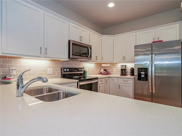 a kitchen with kitchen island a sink stainless steel appliances and white cabinets