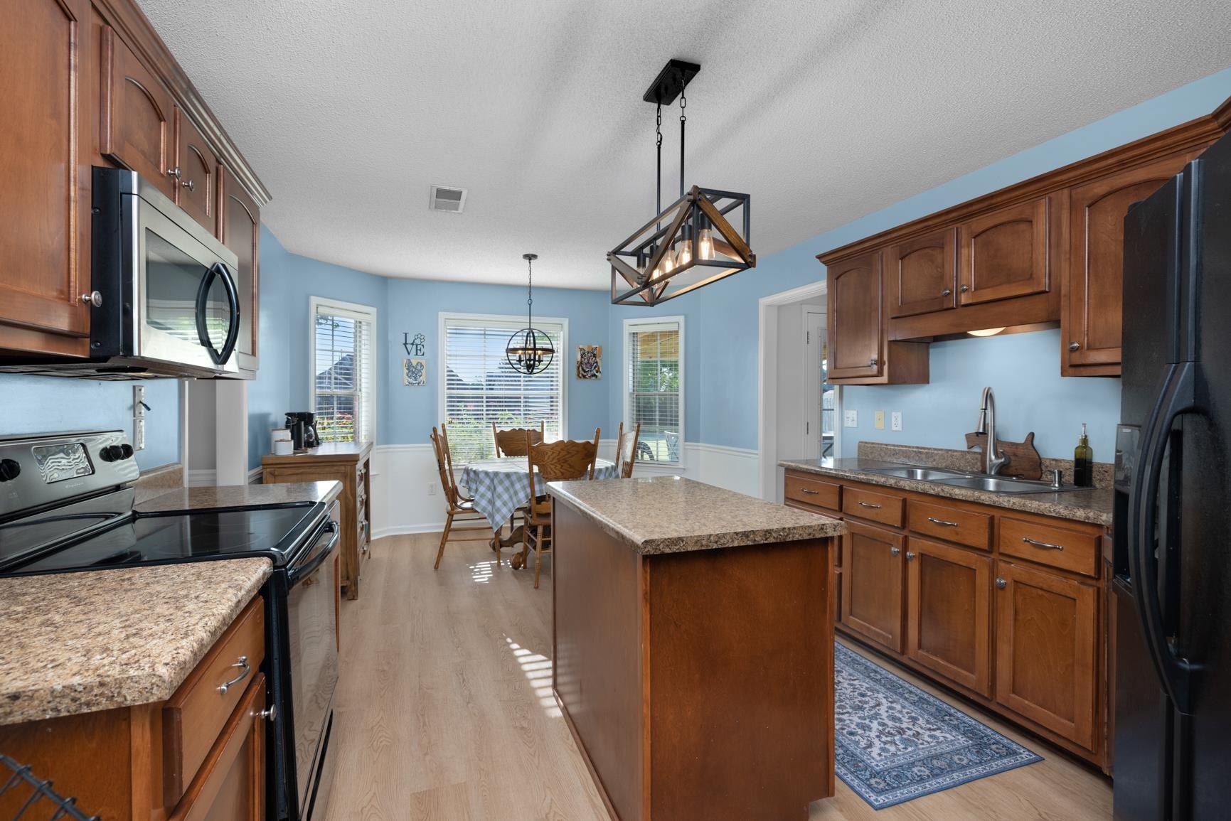 505 Terry Road Oakland, TN 38060 - Photo 16 of 40 Kitchen with electric stove, a center island, black fridge with ice dispenser, stainless steel microwave, and light wood-style floors