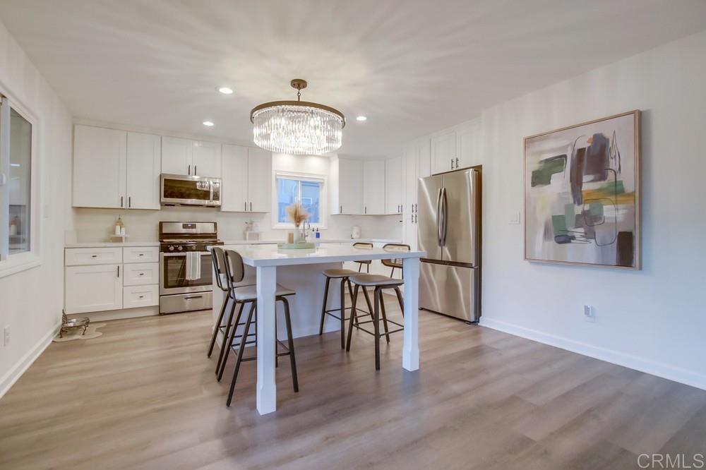 12930 Morene Street Poway, CA 92064 - Photo 12 of 26 a kitchen with stainless steel appliances a dining table chairs refrigerator and microwave