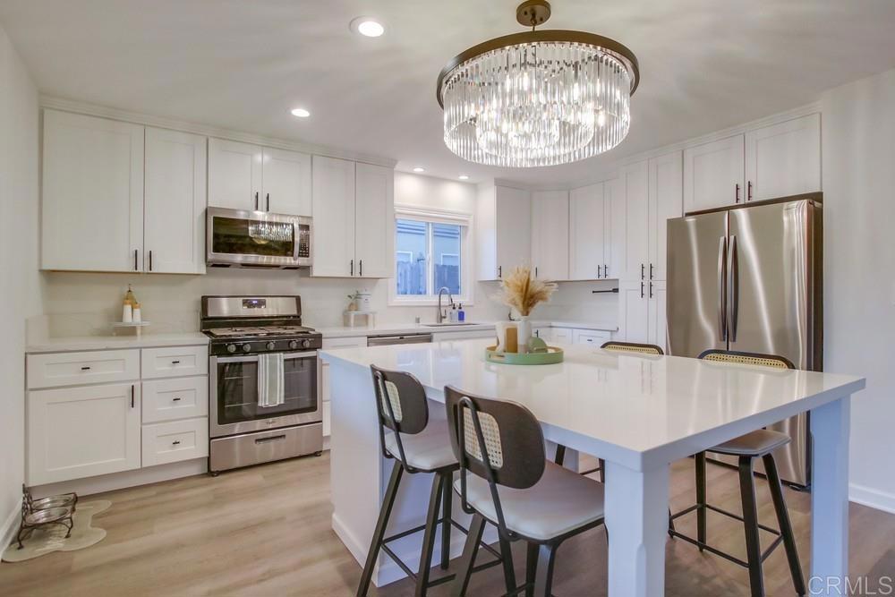 12930 Morene Street Poway, CA 92064 - Photo 14 of 26 a kitchen with stainless steel appliances granite countertop a stove a refrigerator a microwave a sink and chairs