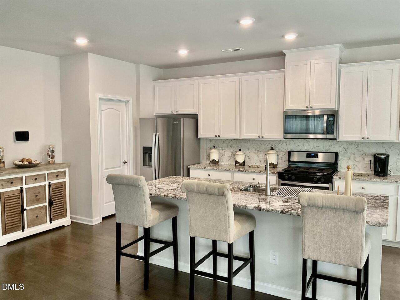 1807 Wrenn Road Durham, NC 27703 - Photo 19 of 43 a kitchen with stainless steel appliances granite countertop a white stove top oven a sink dishwasher and a refrigerator with wooden floor
