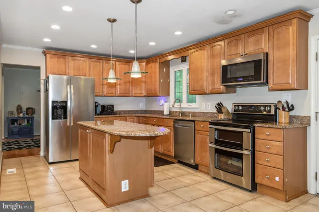 a kitchen with stainless steel appliances granite countertop a refrigerator a stove a sink and a microwave