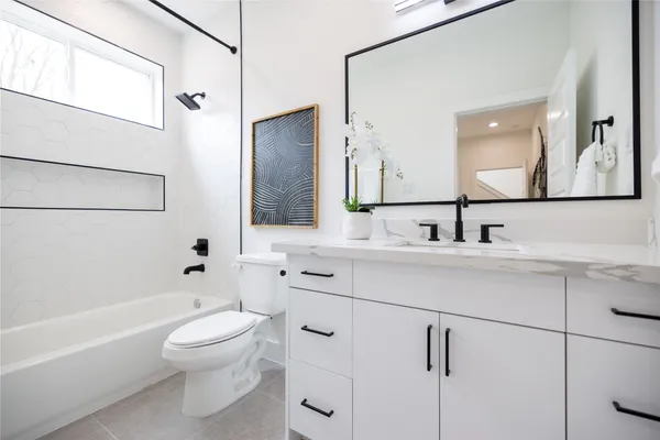 a bathroom with a toilet a sink a mirror a bathtub and vanity