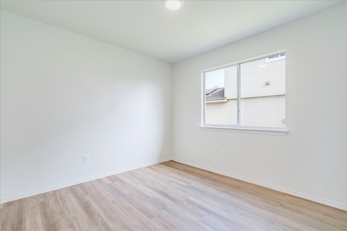 100 Easy Street Hutto, TX 78634 - Photo 18 of 36 A well-lit, neutral room with wood flooring and a wide window offers versatile living possibilities.