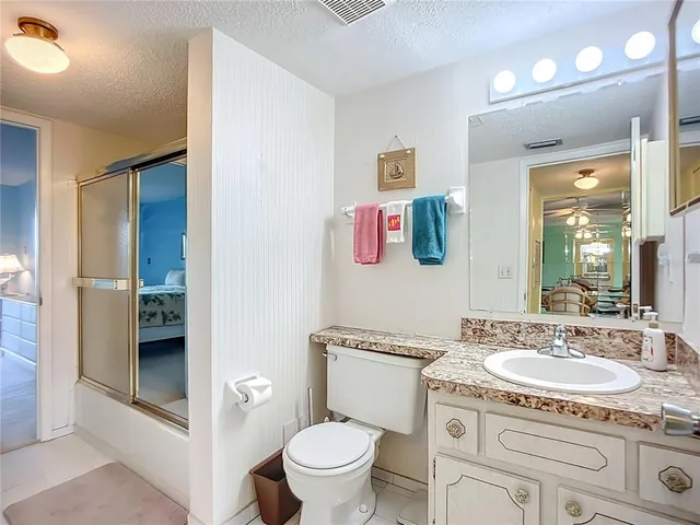 a bathroom with a granite countertop toilet sink and mirror