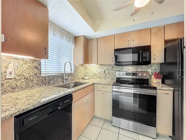 a kitchen with stainless steel appliances granite countertop a sink stove microwave and refrigerator