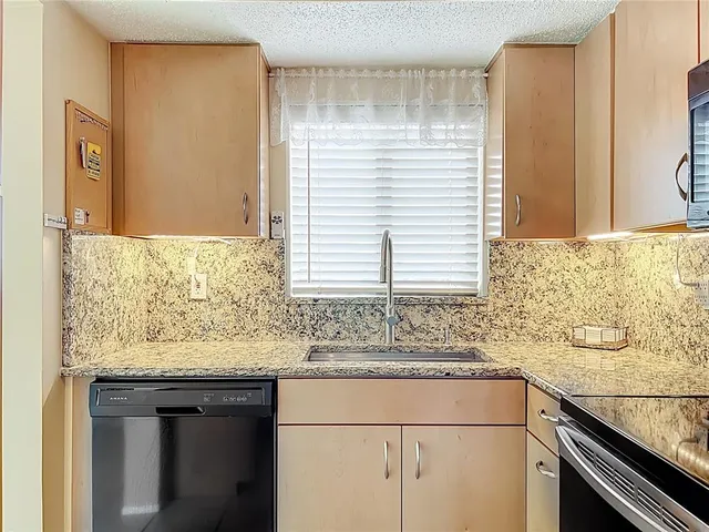 a kitchen with granite countertop sink and cabinets