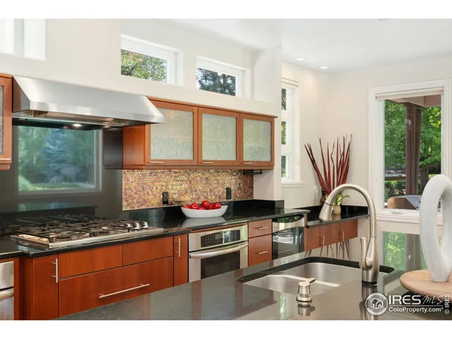 a kitchen with stainless steel appliances granite countertop a sink a stove and a refrigerator