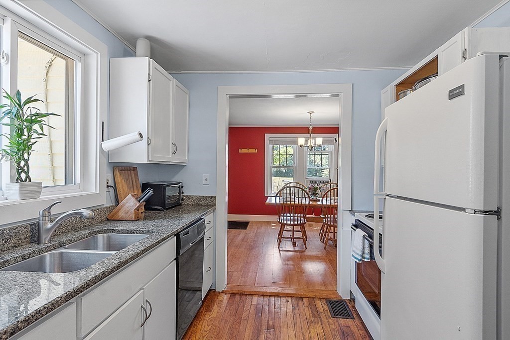 175 Forge Village Road Groton, MA 01450 - Photo 13 of 26 a kitchen with granite countertop a refrigerator a sink a stove and white cabinets with wooden floor