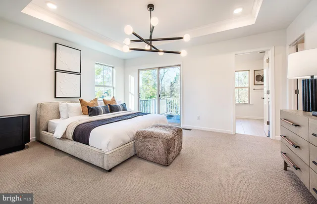 a spacious bedroom with a bed a window and dresser