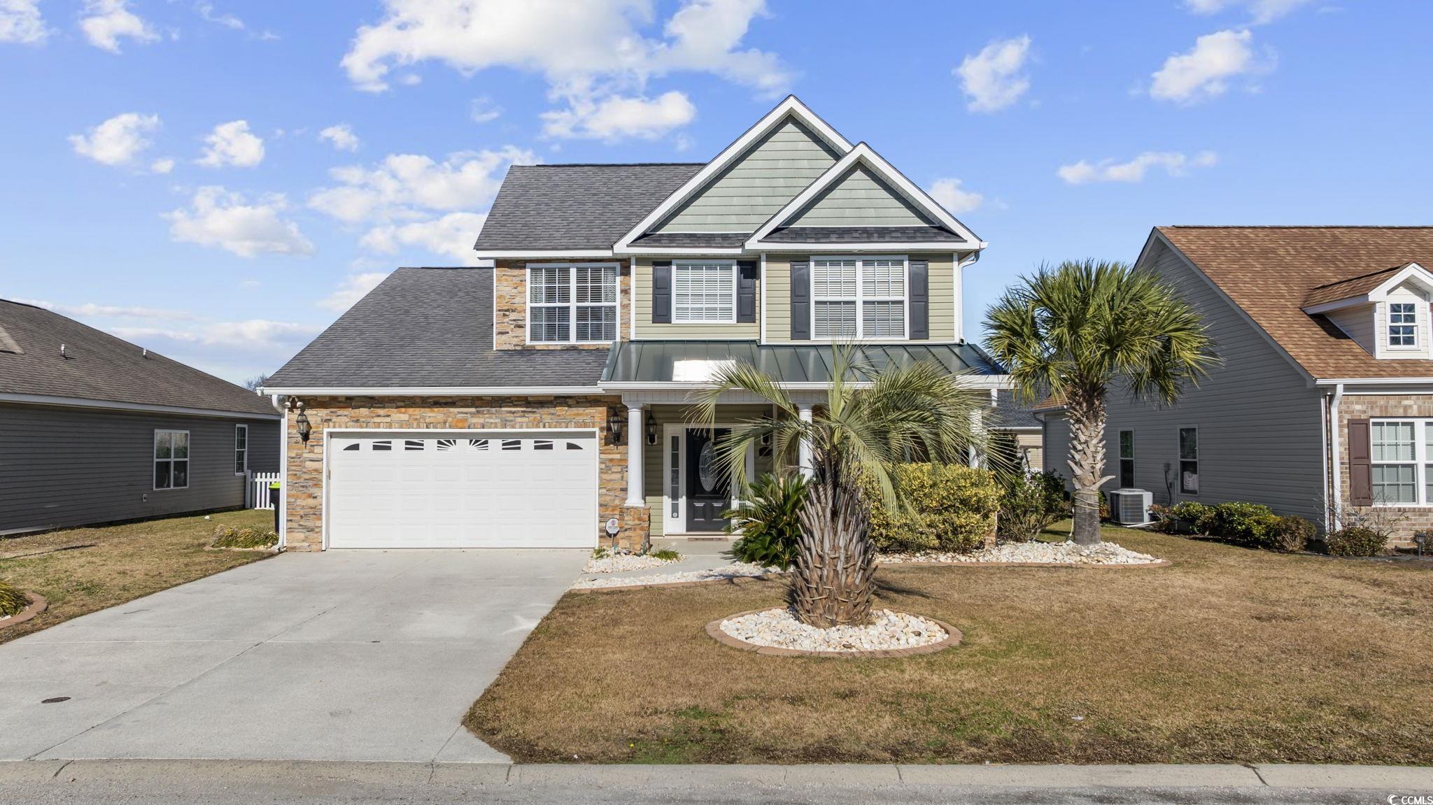 View of front of property with a front lawn, roof with shingles, concrete driveway, and covered porch