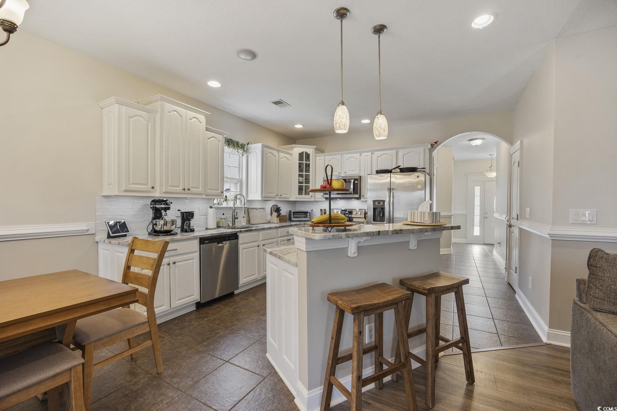418 Cabo Loop Myrtle Beach, SC 29588 - Photo 10 of 40 Kitchen featuring glass insert cabinets, a breakfast bar area, arched walkways, hanging light fixtures, and stainless steel appliances