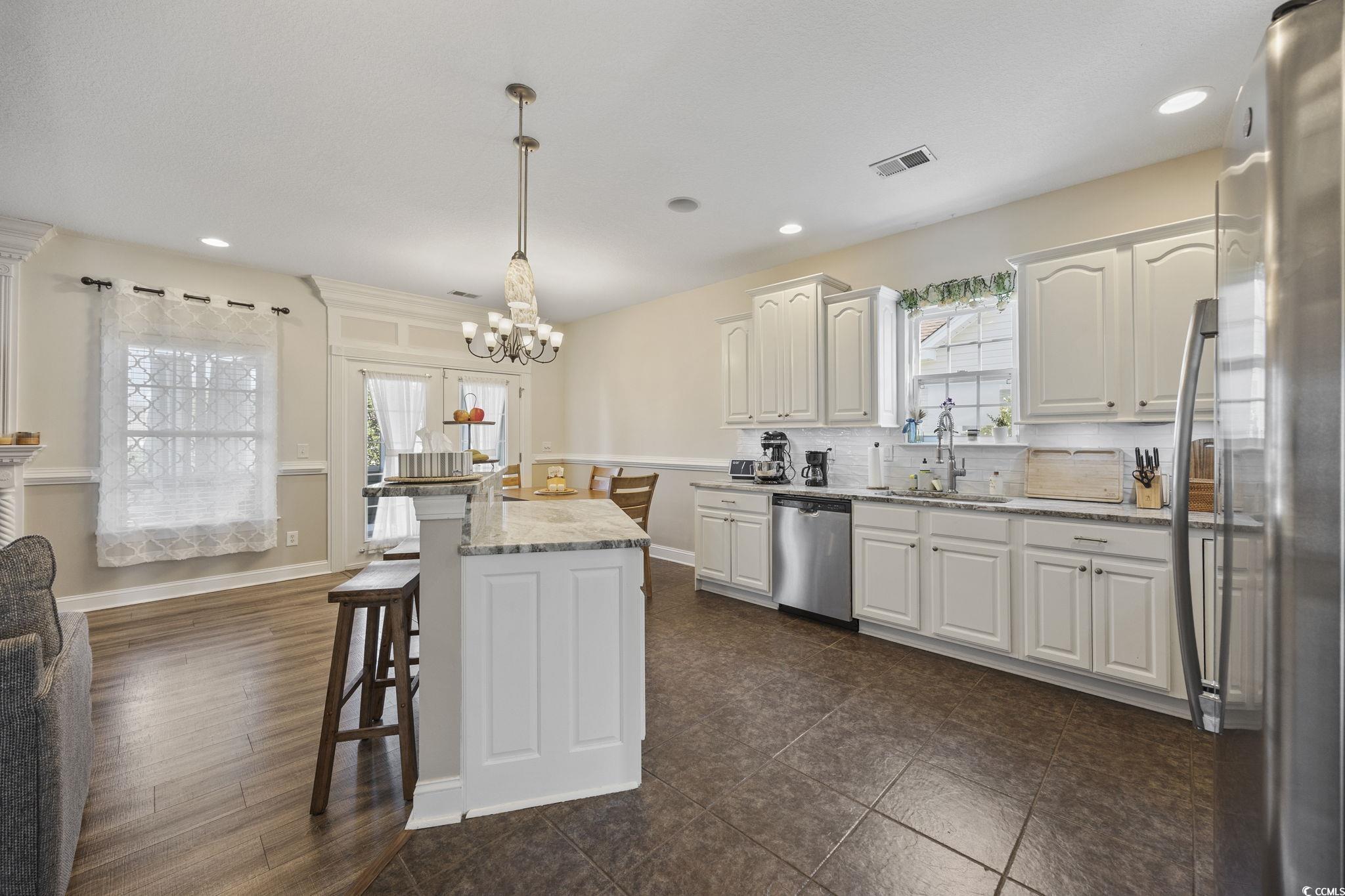 418 Cabo Loop Myrtle Beach, SC 29588 - Photo 11 of 40 Kitchen with appliances with stainless steel finishes, a kitchen bar, light stone counters, hanging light fixtures, and white cabinetry