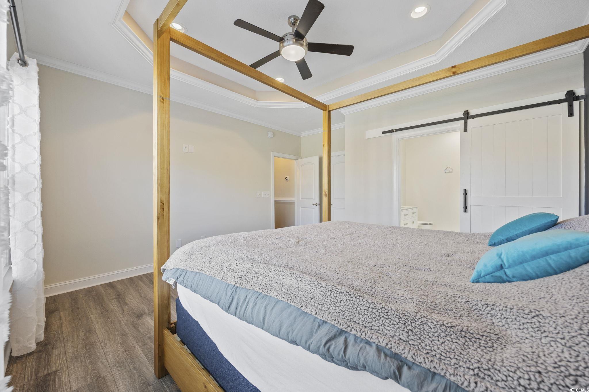 418 Cabo Loop Myrtle Beach, SC 29588 - Photo 14 of 40 Bedroom with a barn door, a raised ceiling, ornamental molding, wood finished floors, and a ceiling fan