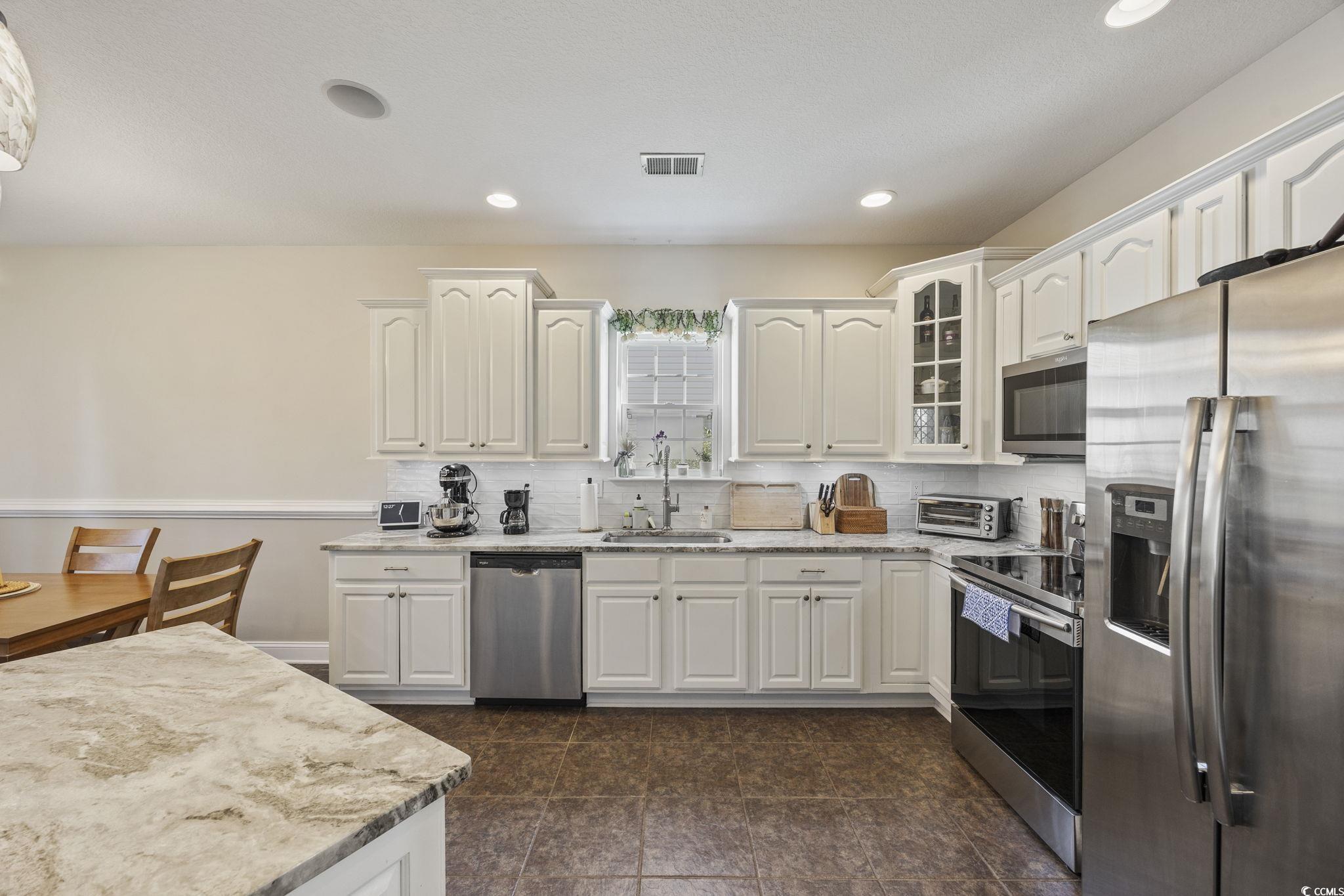418 Cabo Loop Myrtle Beach, SC 29588 - Photo 8 of 40 Kitchen with stainless steel appliances, glass insert cabinets, light stone countertops, decorative backsplash, and white cabinets