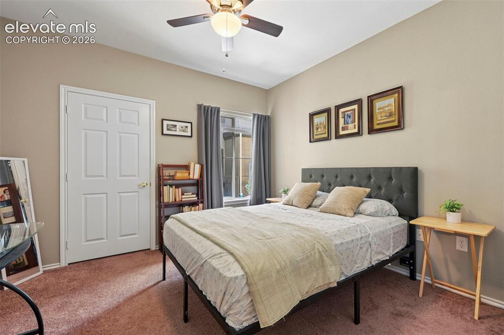 3715 Riviera Grove, Unit 101 Colorado Springs, CO 80922 - Photo 26 of 36 Bedroom featuring a neutral wall color, ceiling fan with light fixture, window with drapes, and a paneled interior door