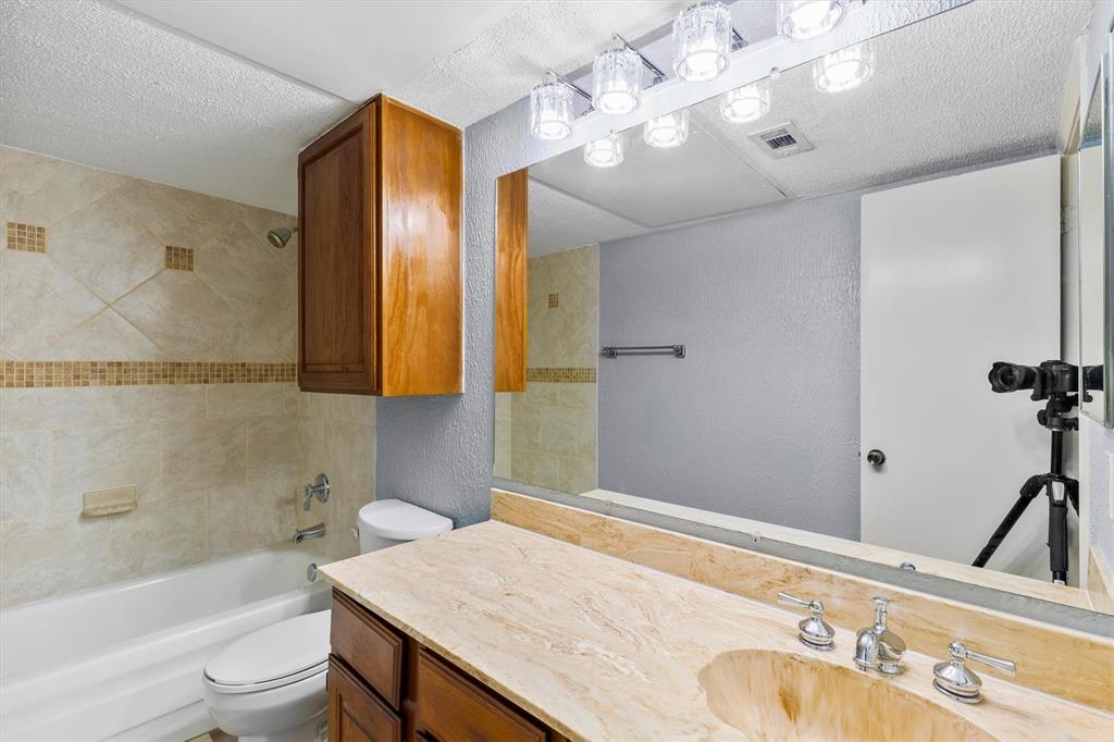 5840 Spring Valley Road, Unit 912 Dallas, TX 75254 - Photo 17 of 33 a bathroom with a granite countertop sink a toilet and shower