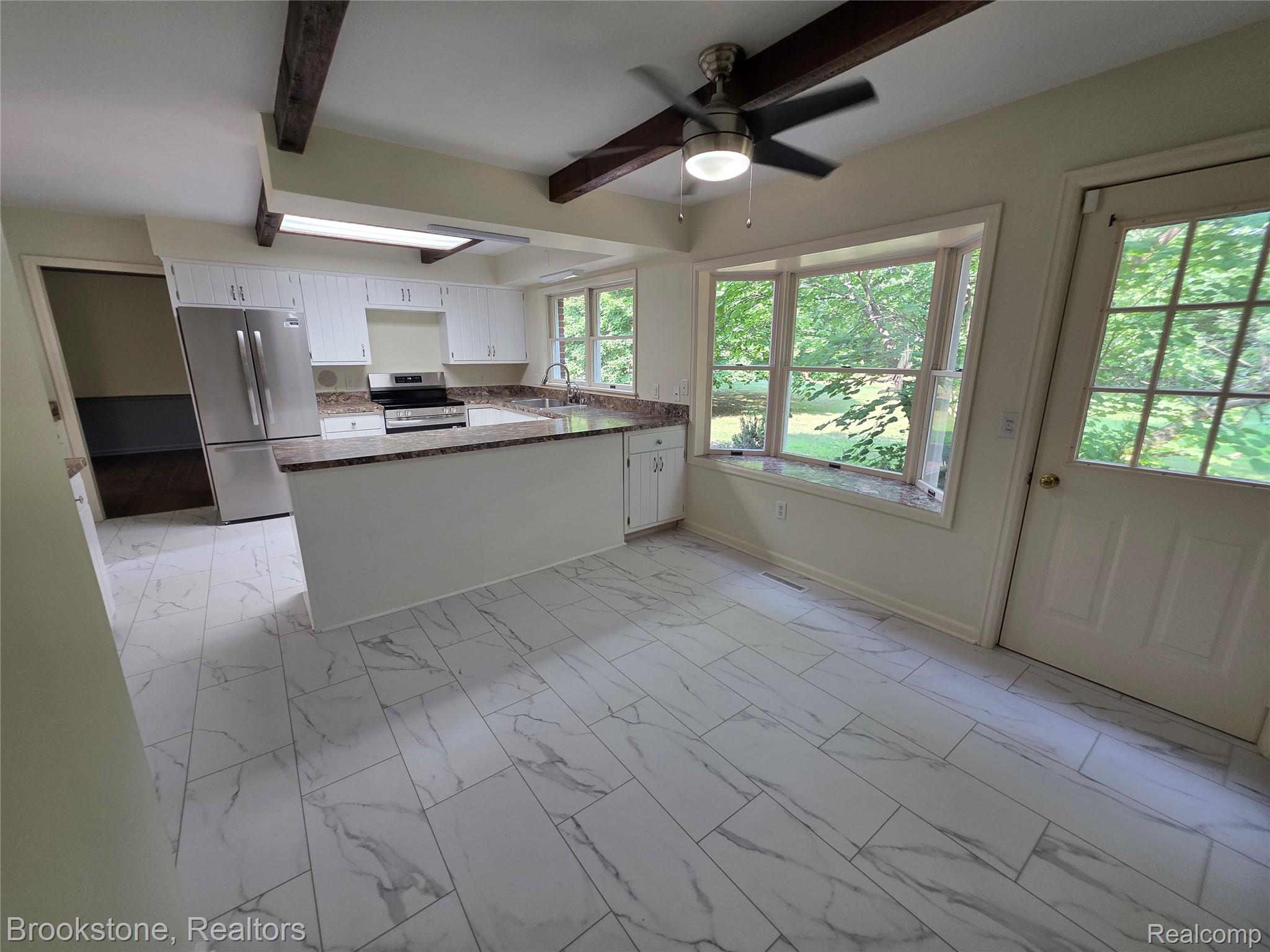 1210 Springborrow Drive Flint, MI 48532 - Photo 17 of 34 Kitchen featuring white cabinetry, granite countertops, stainless steel appliances, and wood-finish ceiling beams