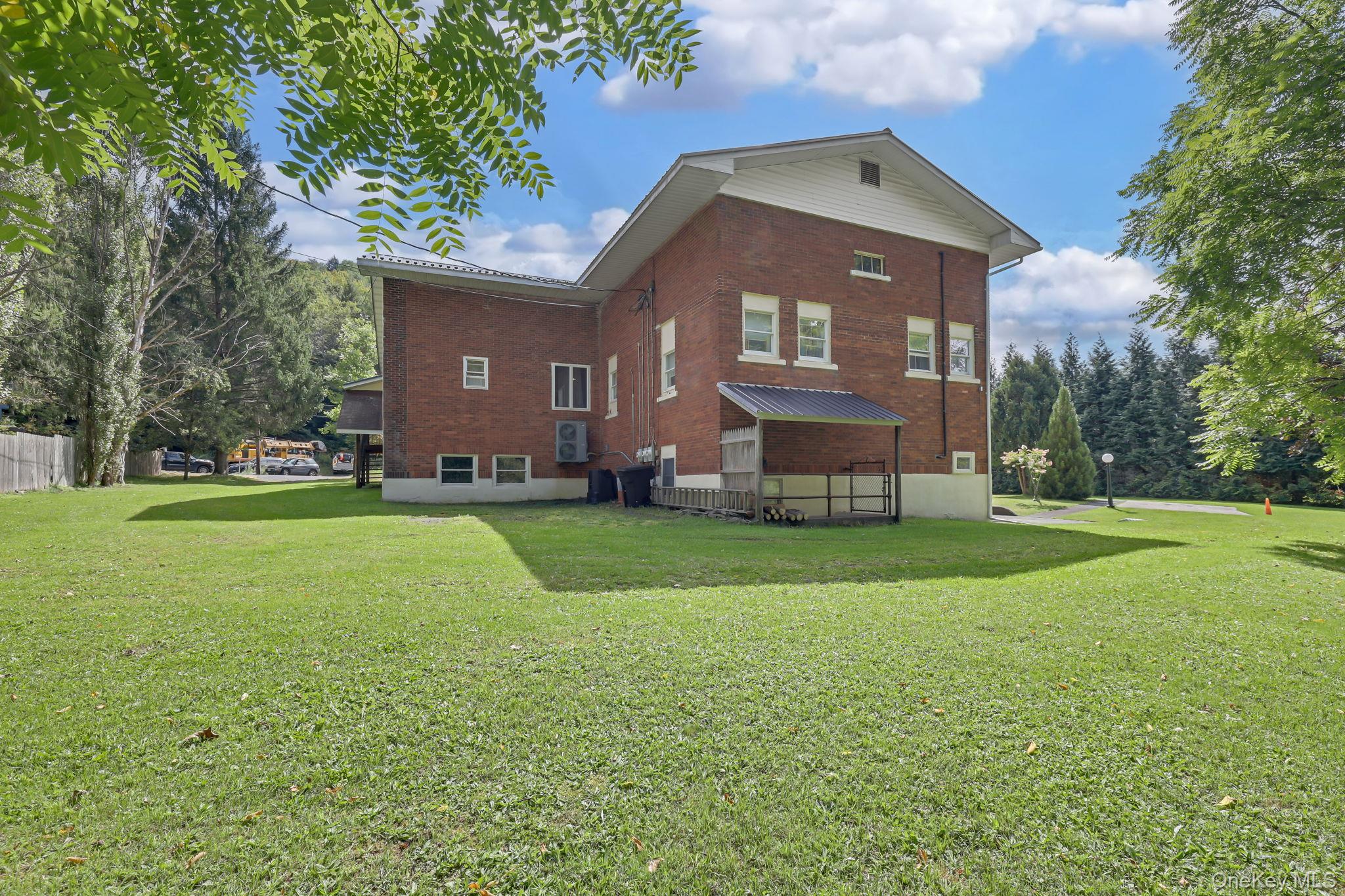 23 Cooley Road Parksville, NY 12768 - Photo 7 of 49 Brick exterior with white trim, covered outdoor area, and a spacious lawn