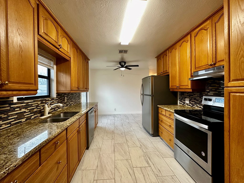 711 Center Street Kerrville, TX 78028 - Photo 2 of 9 a kitchen with stainless steel appliances granite countertop a stove a sink and a refrigerator